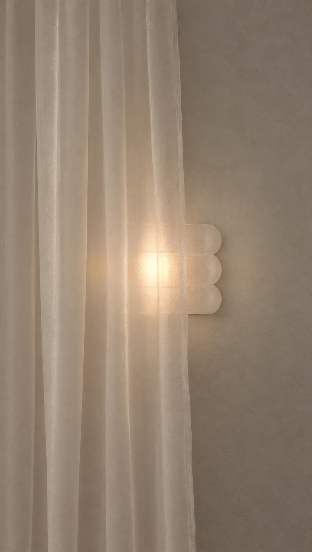 A glowing Mur Mur wall lamp half veiled by a sheer curtain